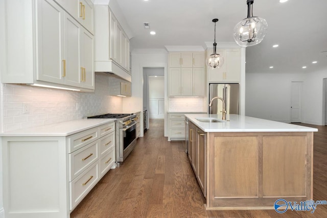 kitchen with appliances with stainless steel finishes, sink, white cabinets, hanging light fixtures, and a spacious island