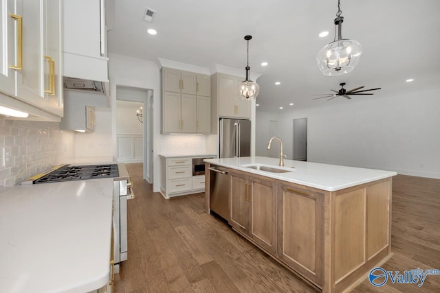 kitchen with a spacious island, sink, decorative light fixtures, light hardwood / wood-style flooring, and stainless steel appliances