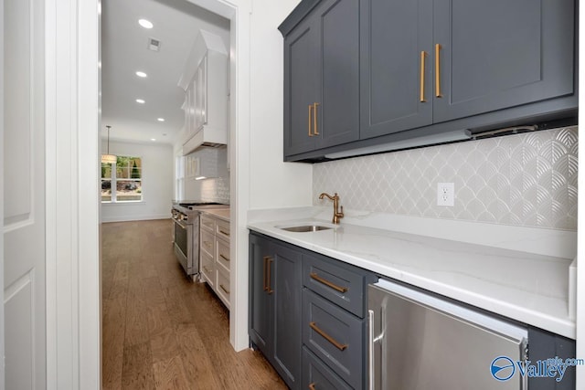 kitchen with gray cabinetry, sink, stainless steel range, and hardwood / wood-style flooring