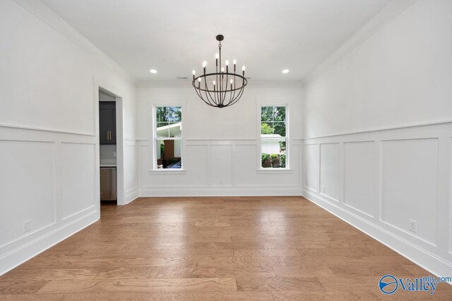 unfurnished dining area with light hardwood / wood-style floors, an inviting chandelier, and crown molding