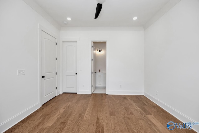 unfurnished bedroom with ensuite bath, ceiling fan, and hardwood / wood-style floors