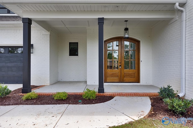 property entrance featuring a garage, french doors, and covered porch