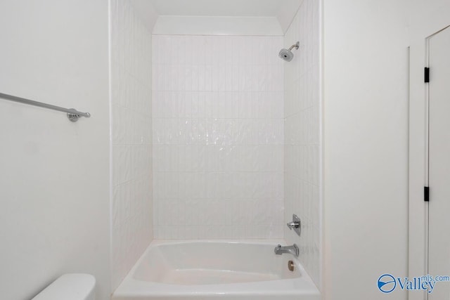 bathroom featuring toilet and tiled shower / bath