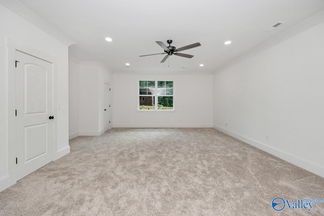 spare room featuring light colored carpet, ceiling fan, and crown molding