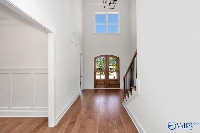 entrance foyer featuring french doors, hardwood / wood-style floors, and a high ceiling