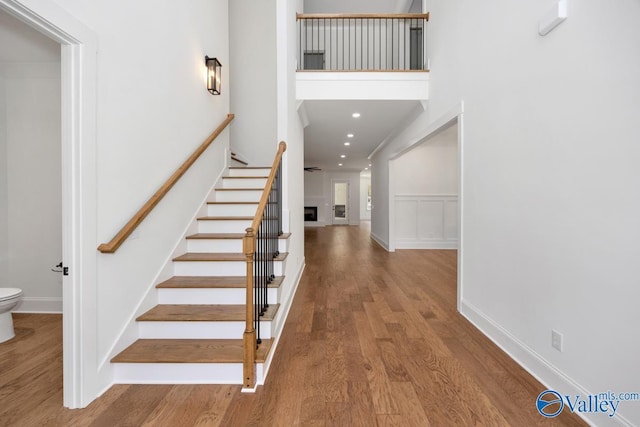 stairs with wood-type flooring and a high ceiling