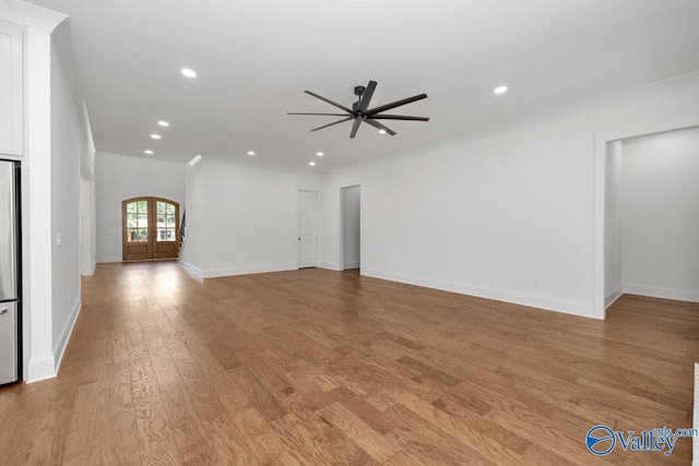 unfurnished living room featuring light hardwood / wood-style floors, ceiling fan, and crown molding