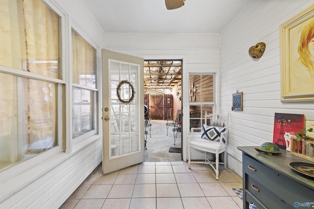 doorway to outside with crown molding and light tile patterned floors