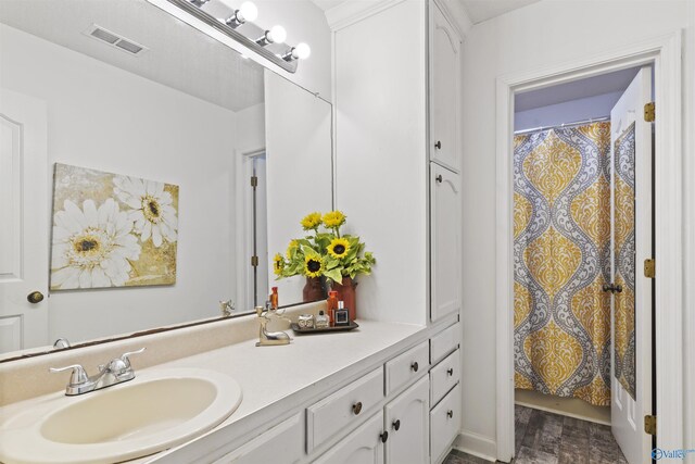 full bath featuring a shower with curtain, visible vents, wood finished floors, and vanity