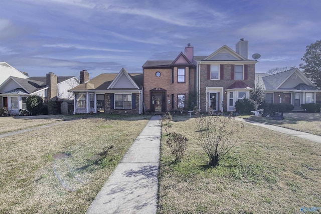 view of front of house with a chimney, a front lawn, and brick siding
