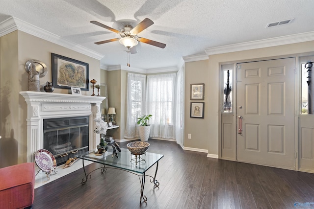 living room with a textured ceiling, visible vents, ornamental molding, a ceiling fan, and dark wood-type flooring