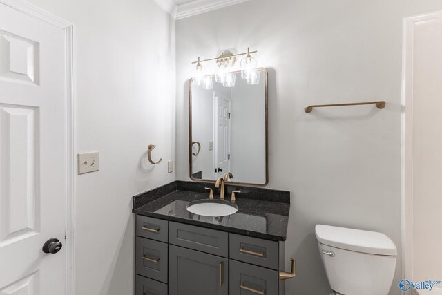 bathroom with toilet, vanity, and ornamental molding