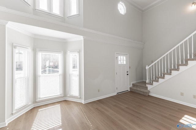 foyer entrance with hardwood / wood-style floors, crown molding, and a high ceiling