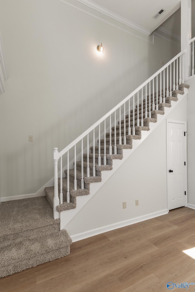 stairs featuring hardwood / wood-style flooring and crown molding