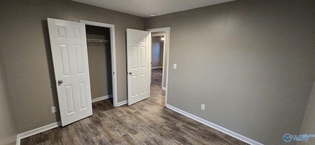 unfurnished bedroom with dark wood-type flooring and a closet