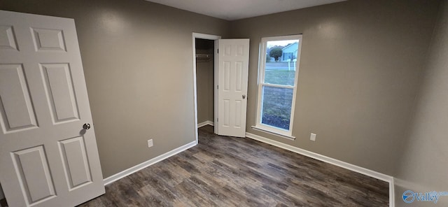 unfurnished bedroom with dark hardwood / wood-style flooring and a closet