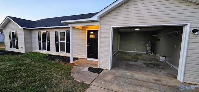 doorway to property with a lawn, electric water heater, and a garage