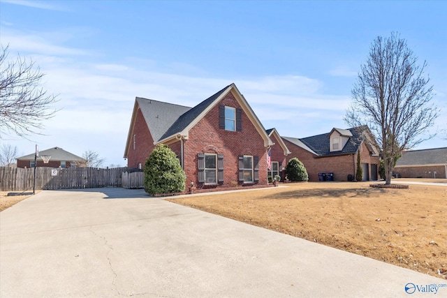 traditional-style house featuring driveway, fence, and brick siding