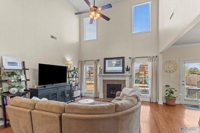 living room featuring a fireplace, wood finished floors, visible vents, and baseboards