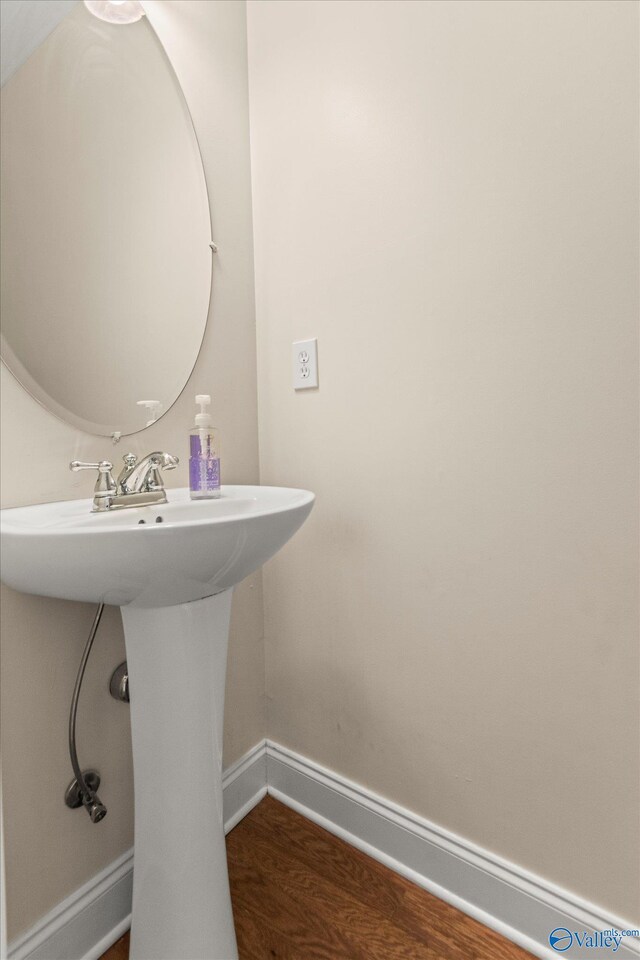 bathroom featuring a sink, baseboards, and wood finished floors