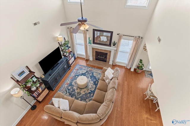 living area with a healthy amount of sunlight, visible vents, wood finished floors, and a tile fireplace