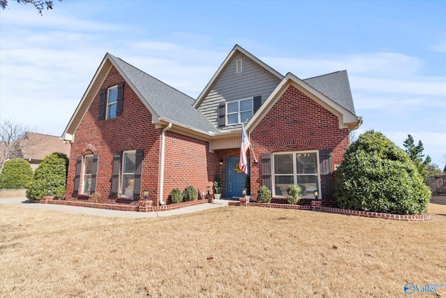 traditional home with brick siding, roof with shingles, and a front yard