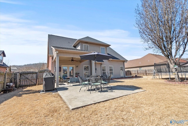 rear view of property featuring a trampoline, a lawn, a ceiling fan, a patio area, and a fenced backyard