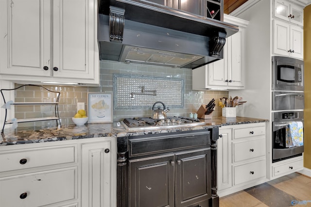 900 Menominee Rd, Langston, AL 35755 - kitchen with appliances with stainless steel finishes, range hood, white cabinetry, and backsplash