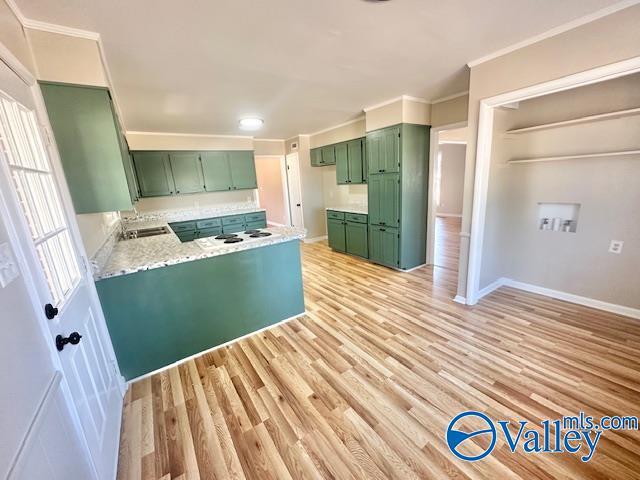 kitchen with ornamental molding, light wood-type flooring, a peninsula, and green cabinets