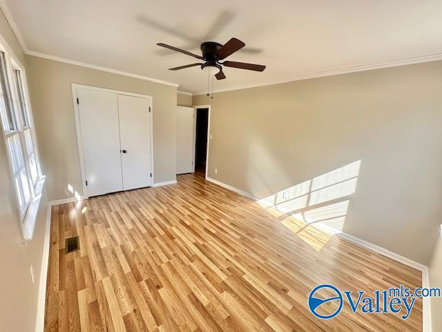 unfurnished bedroom with light wood-style floors, visible vents, ornamental molding, and baseboards