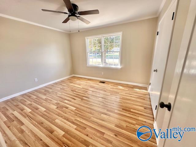 unfurnished bedroom with light wood-type flooring, baseboards, and ornamental molding