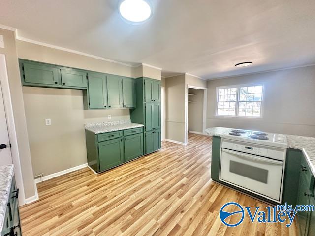 kitchen featuring white appliances, baseboards, crown molding, light wood-style floors, and green cabinetry