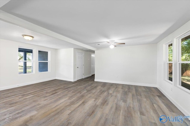 empty room featuring dark wood-type flooring, ceiling fan, and plenty of natural light