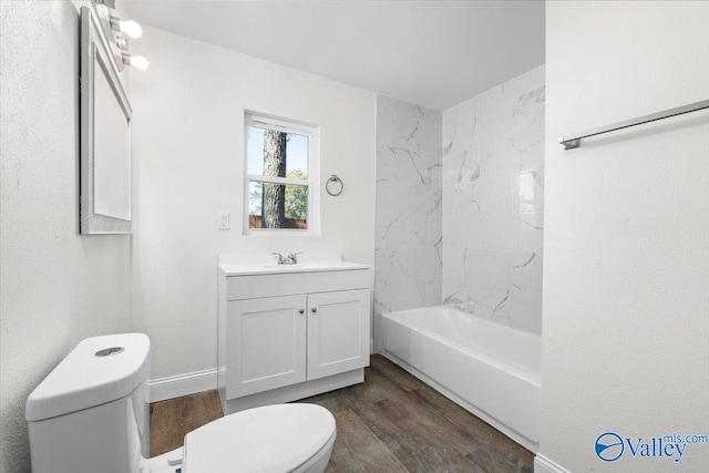 full bathroom with vanity, toilet, tiled shower / bath, and hardwood / wood-style floors