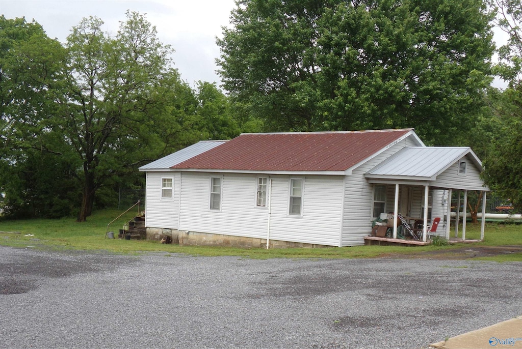 view of property exterior featuring a porch, metal roof, and crawl space