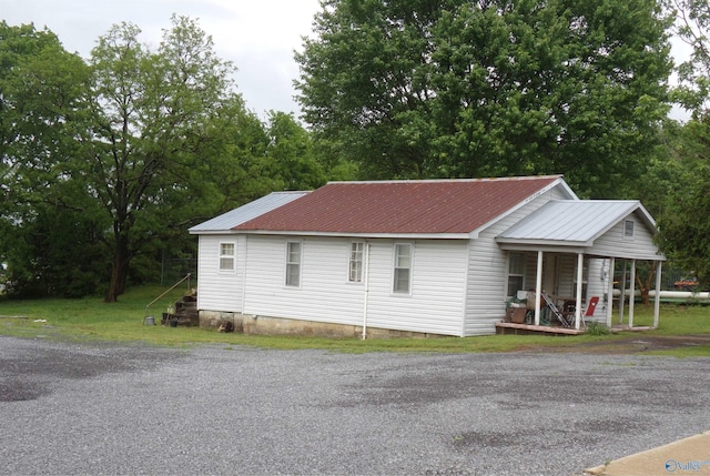 view of property exterior featuring a porch, metal roof, and crawl space