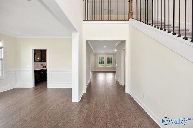 entryway with ornamental molding and dark wood-type flooring