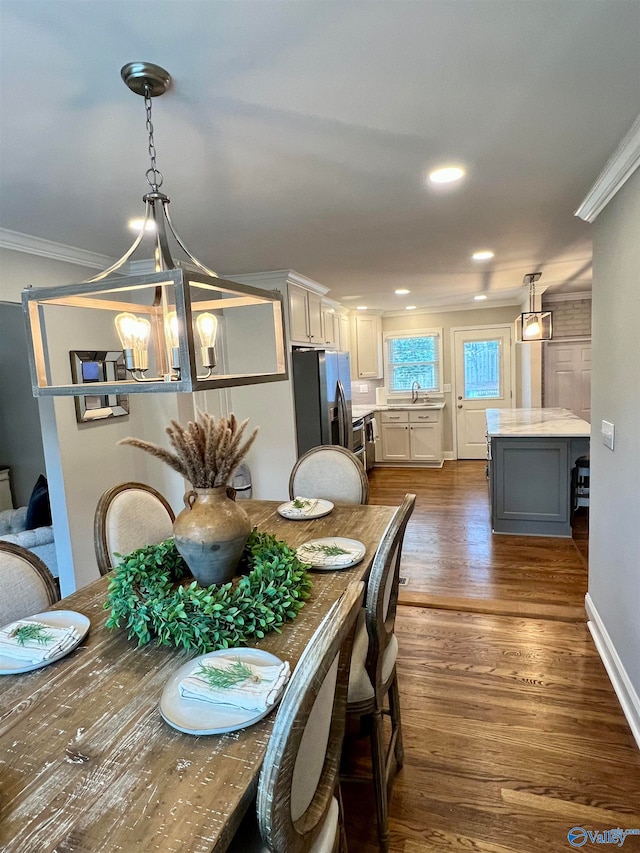 dining room with dark hardwood / wood-style flooring, an inviting chandelier, ornamental molding, and sink