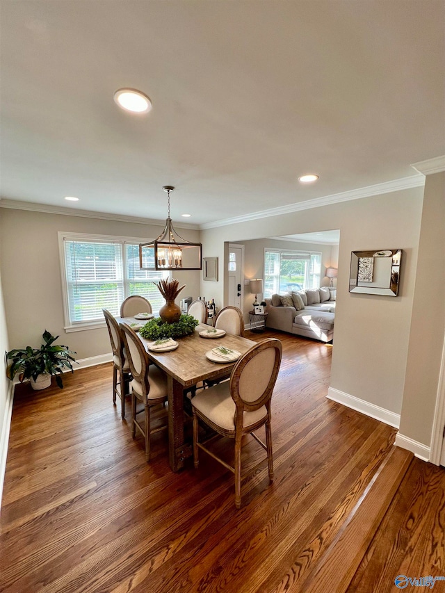 dining room with a notable chandelier, crown molding, and dark wood-type flooring