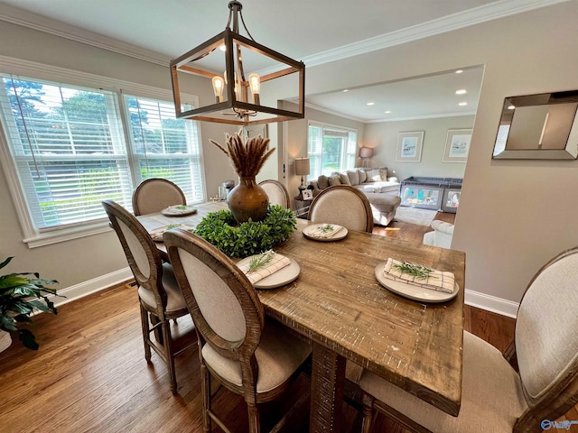 dining area with a chandelier, wood-type flooring, and ornamental molding