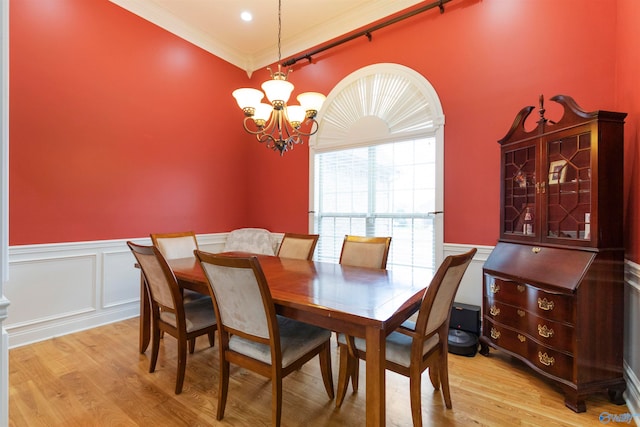 dining space with light wood-type flooring, crown molding, and a notable chandelier