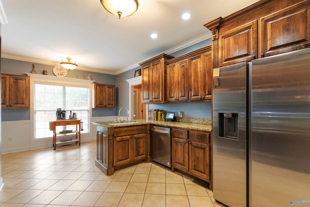 kitchen with light stone counters, sink, kitchen peninsula, stainless steel appliances, and ornamental molding