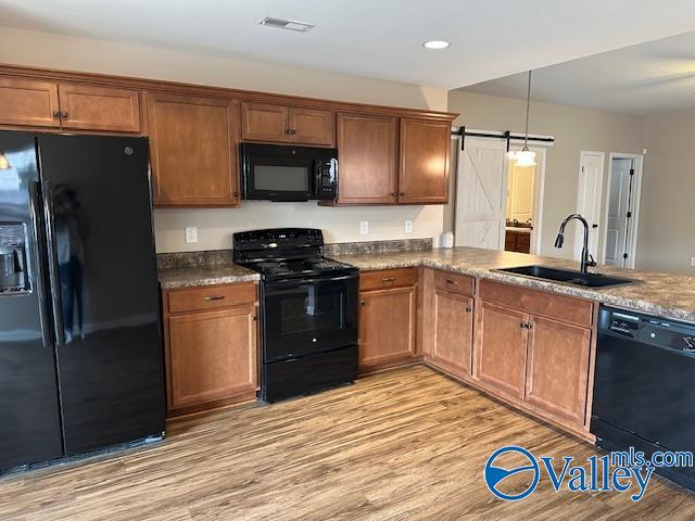 134 Winstead Cir, Owens Cross Roads, AL 35763 - kitchen with visible vents, a sink, light wood-type flooring, black appliances, and brown cabinetry