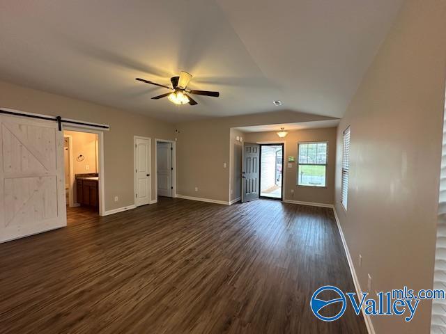 134 Winstead Cir, Owens Cross Roads, AL 35763 - unfurnished living room with baseboards, a ceiling fan, dark wood finished floors, a barn door, and vaulted ceiling
