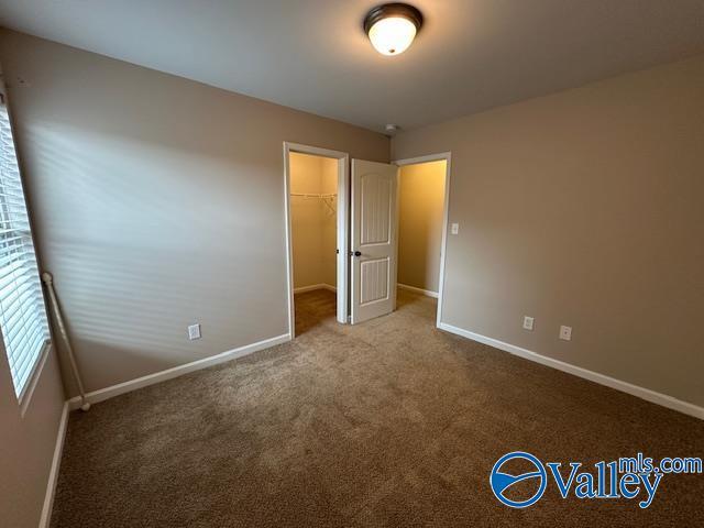 134 Winstead Cir, Owens Cross Roads, AL 35763 - unfurnished bedroom featuring baseboards, a closet, a walk in closet, and carpet