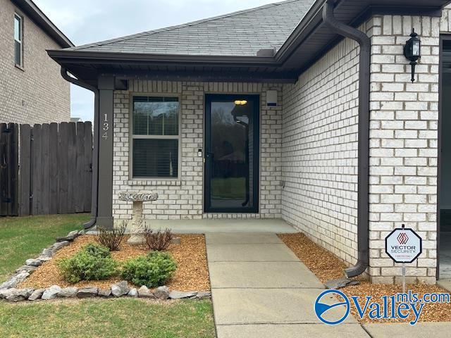 134 Winstead Cir, Owens Cross Roads, AL 35763 - property entrance with a shingled roof, fence, and brick siding