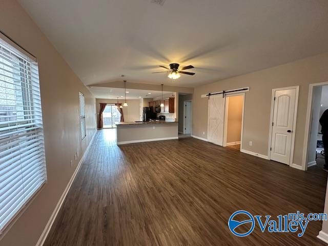 134 Winstead Cir, Owens Cross Roads, AL 35763 - unfurnished living room with baseboards, a barn door, ceiling fan, and dark wood-type flooring