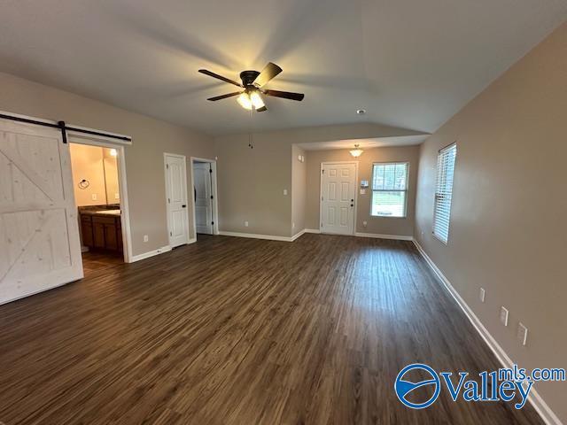 134 Winstead Cir, Owens Cross Roads, AL 35763 - unfurnished living room featuring baseboards, dark wood-style flooring, a barn door, and a ceiling fan