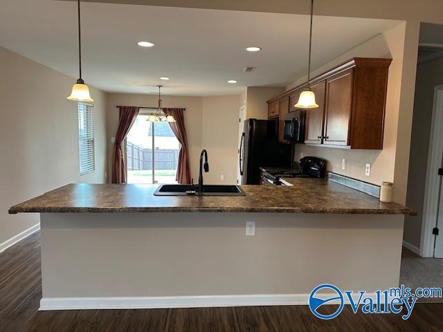 134 Winstead Cir, Owens Cross Roads, AL 35763 - kitchen featuring range with gas stovetop, a peninsula, stainless steel microwave, a sink, and pendant lighting