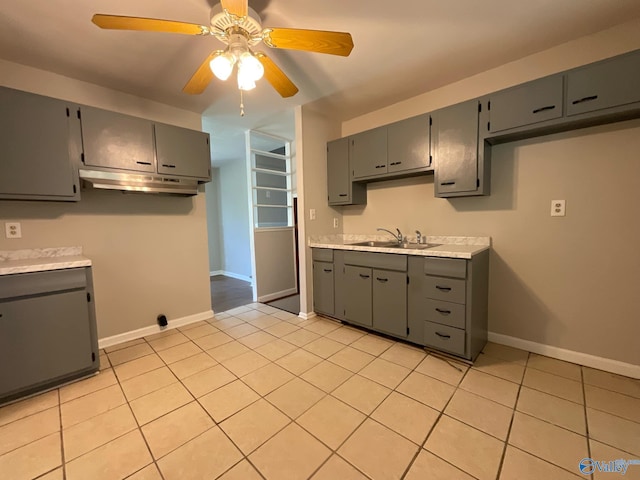 kitchen featuring a sink, gray cabinets, and under cabinet range hood
